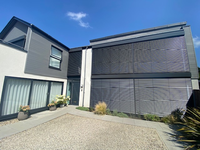 Modern home fitted with dark grey external venetian blinds across large front-facing windows