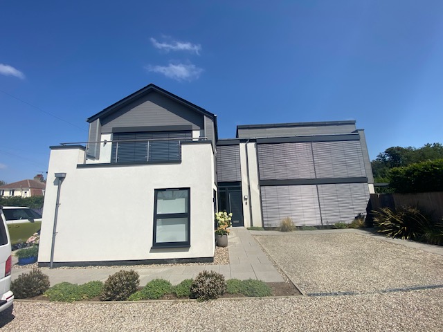 Front elevation of a modern home with sleek external venetian blinds covering large windows beside the driveway